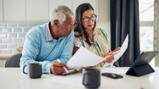 Older couple sitting at their kitchen table reviewing financial documents.