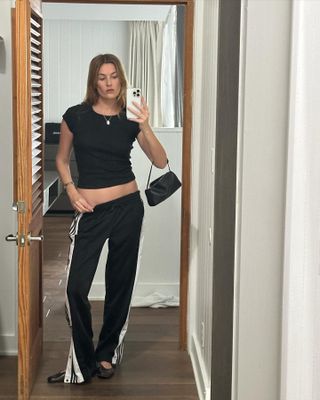 Camille Charriere wears Adidas firebird track pants, black baby t-shirt and ballet flats.