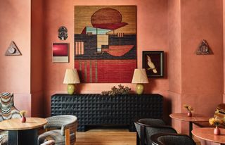 A restaurant with pink walls and a black console