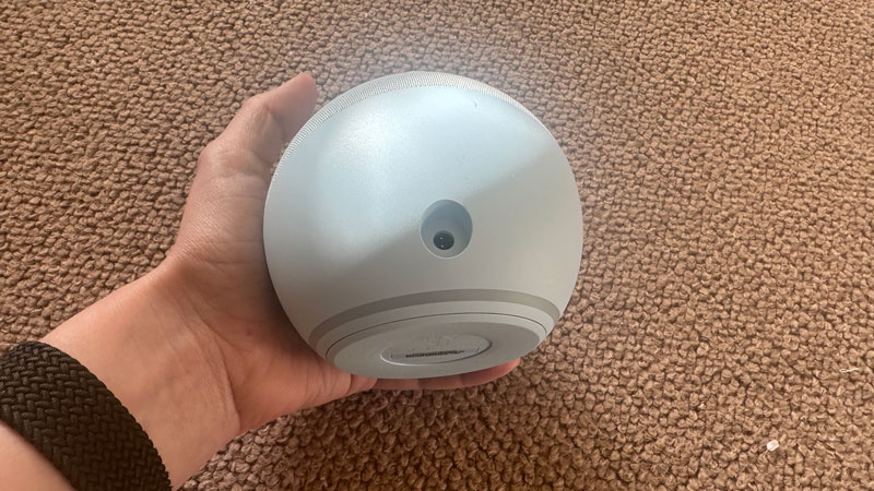 Alguém segurando o Echo Dot para que a conexão traseira e do cabo de alimentação fique visível