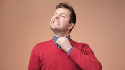 Man tries to loosen his collar, which is too tight.