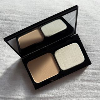 An open Bobbi Brown Skin Weightless Powder Foundation in the shade Warm Ivory, sitting on a white linen backdrop