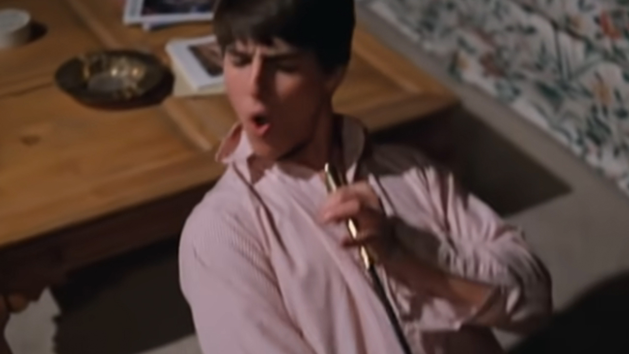 Tom Cruise singing into a candlestick and wearing a pink shirt in Risky Business.