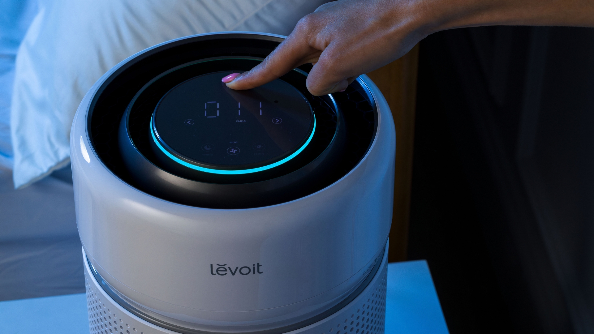 Levoit air purifier with controls on top in a dark bedroom