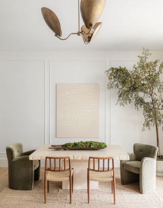 Stone dining table with two pale sage velvet armchairs and two wood and woven dining chairs