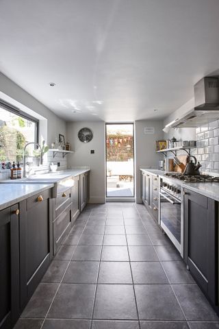 Jason Traves house: Galley kitchen with dark units, white metro tiles and grey square floor tiles