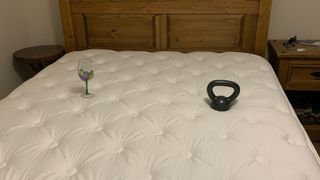 The WinkBed Mattress shown with a wine glass on one side and a black 10lb weight on the other