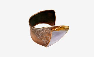 A shell textured wrist cuff bracelet with a thick strap.