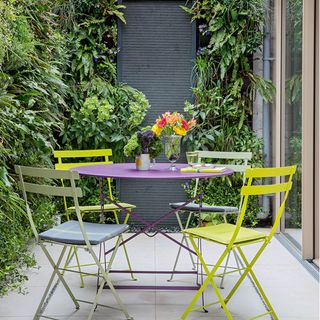 grey wall panel with yellow garden chairs and purple table
