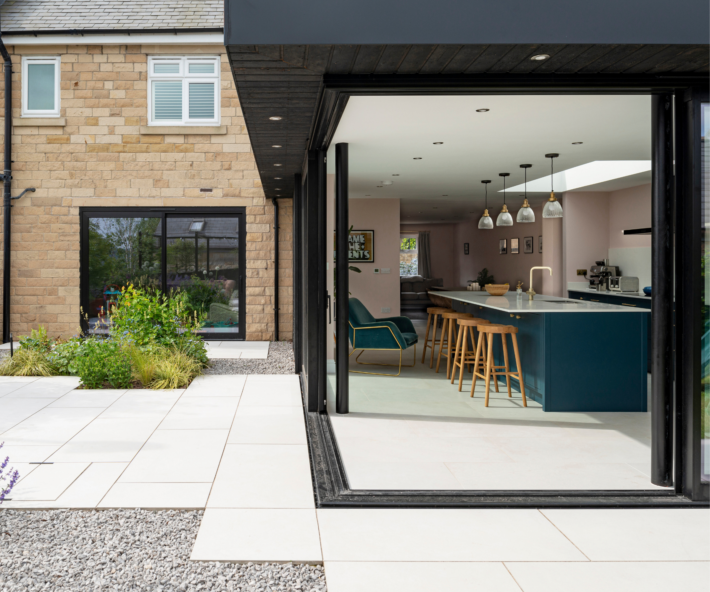 Glass box extension with the doors open revealing an open plan kitchen diner inside