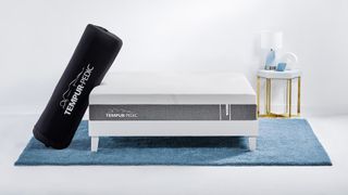 The Tempur-Pedic Tempur-Cloud mattress rolled up in a black shipping bag and leaning against a mattress