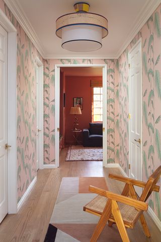 pink and green palm leaf wallpaper in a hallway