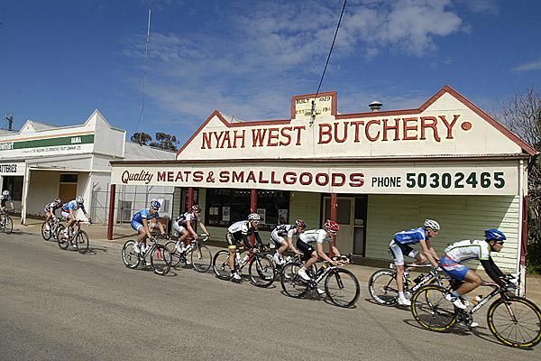Riders pass an old butcher's shop in Nyah West during stage six of the tour.