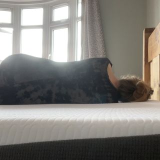 reviewer lying on side during testing the REM-Fit Hybrid 1000 mattress