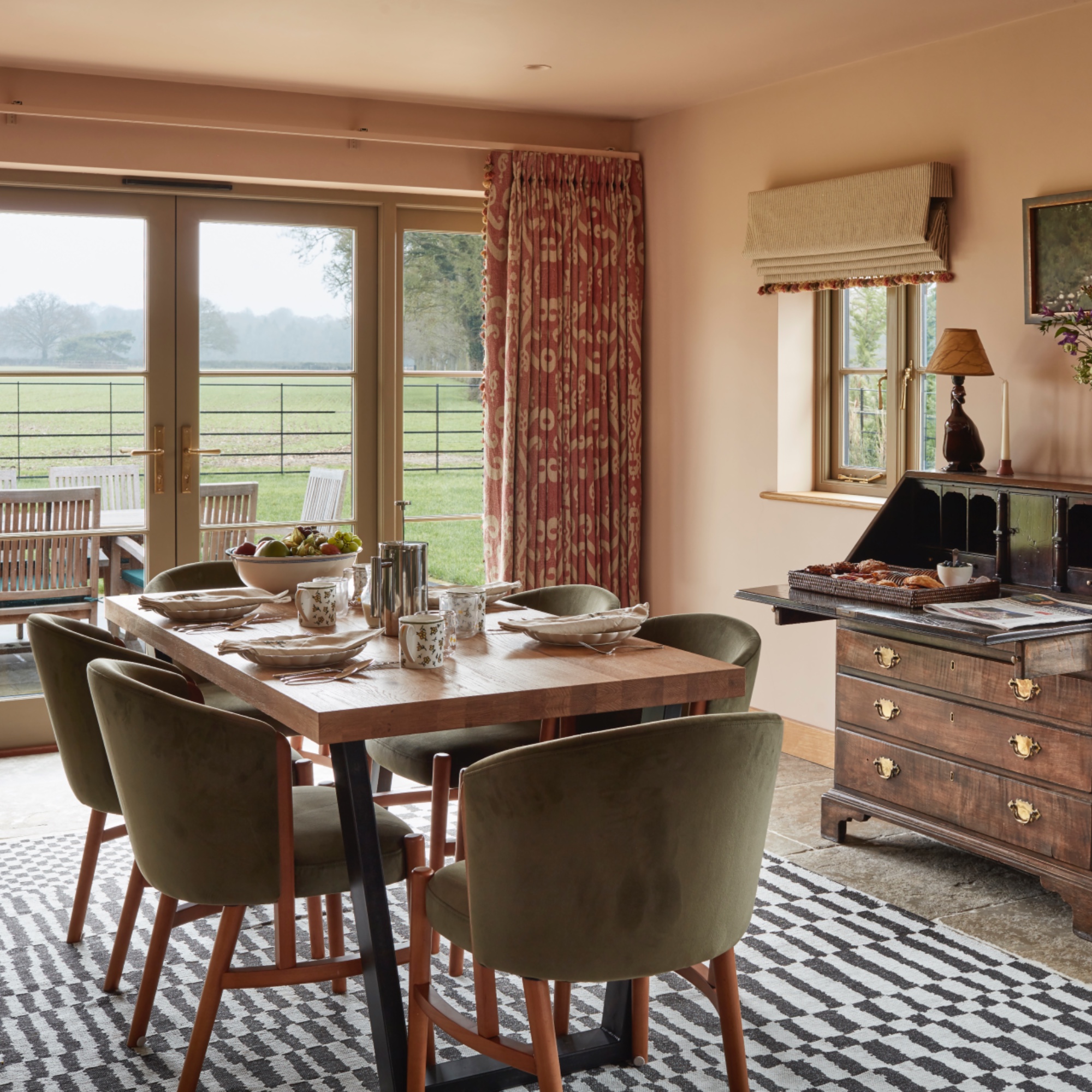 dining room area with monochromatic rug, green velvet dining chairs, writing desk