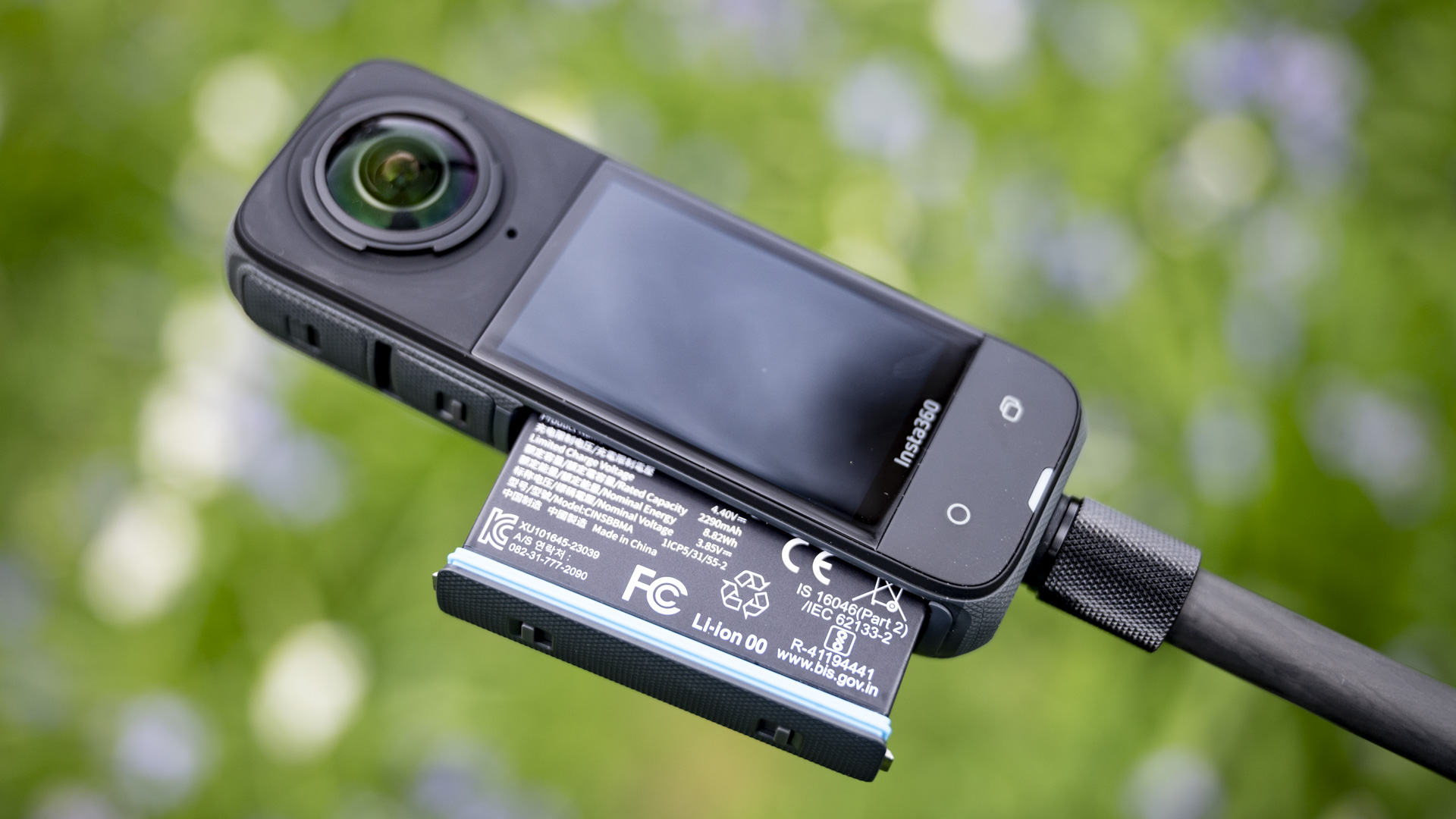 Battery of Insta360 X4 360 degree camera outdoors with vibrant grassy background