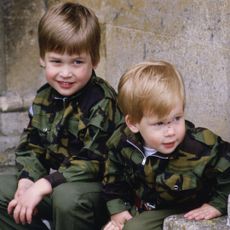 Prince Harry and Prince William sit together on the steps of Highgrove House wearing army uniforms on July 18, 1986