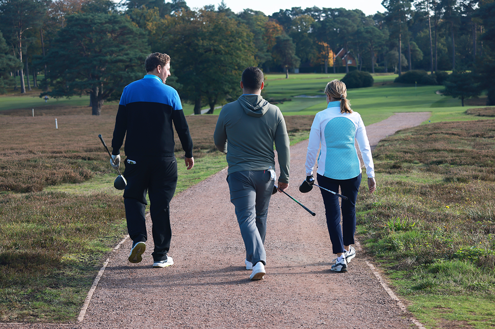 A three-ball consisting of Alison Root, Nick Bonfield and Sam De'Ath walking together down a path on the course at West Hill Golf Club