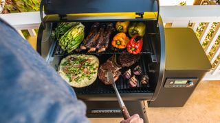 Traeger Ironwood 650 wood pellet BBQ in use by an adult human male