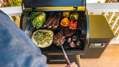 Traeger Ironwood 650 smoker being used by a man to smoke vegetables and meat