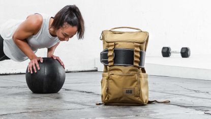 Best gym bag: Pictured here, a fit young female athlete doing medicine ball push-ups next to the CORE25 gym bag