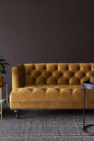 living room with dark interior scheme and mustard yellow chesterfield sofa by rockett st george