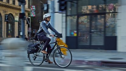 Best commuter bike pedals: Image shows a man riding a commuter bike with flat pedals through the city
