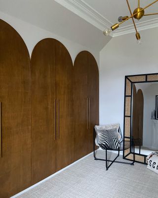 A bedroom with a large wardrobe with arched wooden doors