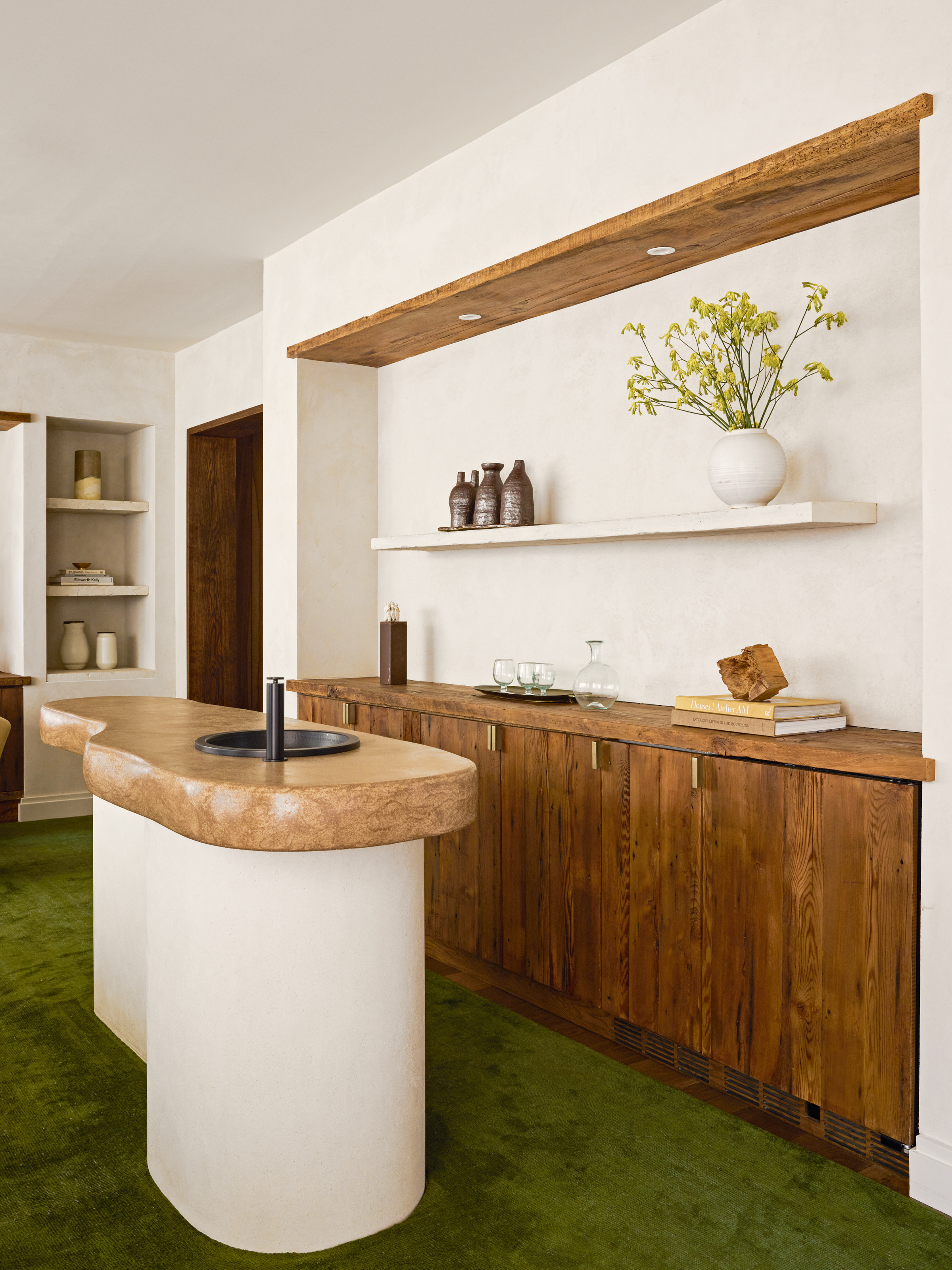 Kitchen with wood cabinets, rounded island, plaster walls and green carpet
