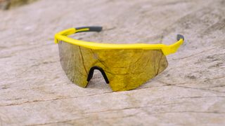 A pair of yellow and gold sunglasses on a wooden bench