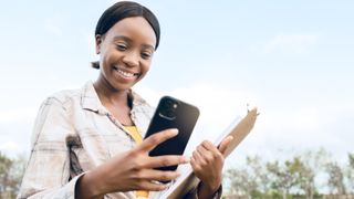 Woman holding iPhone and clipboard in a field