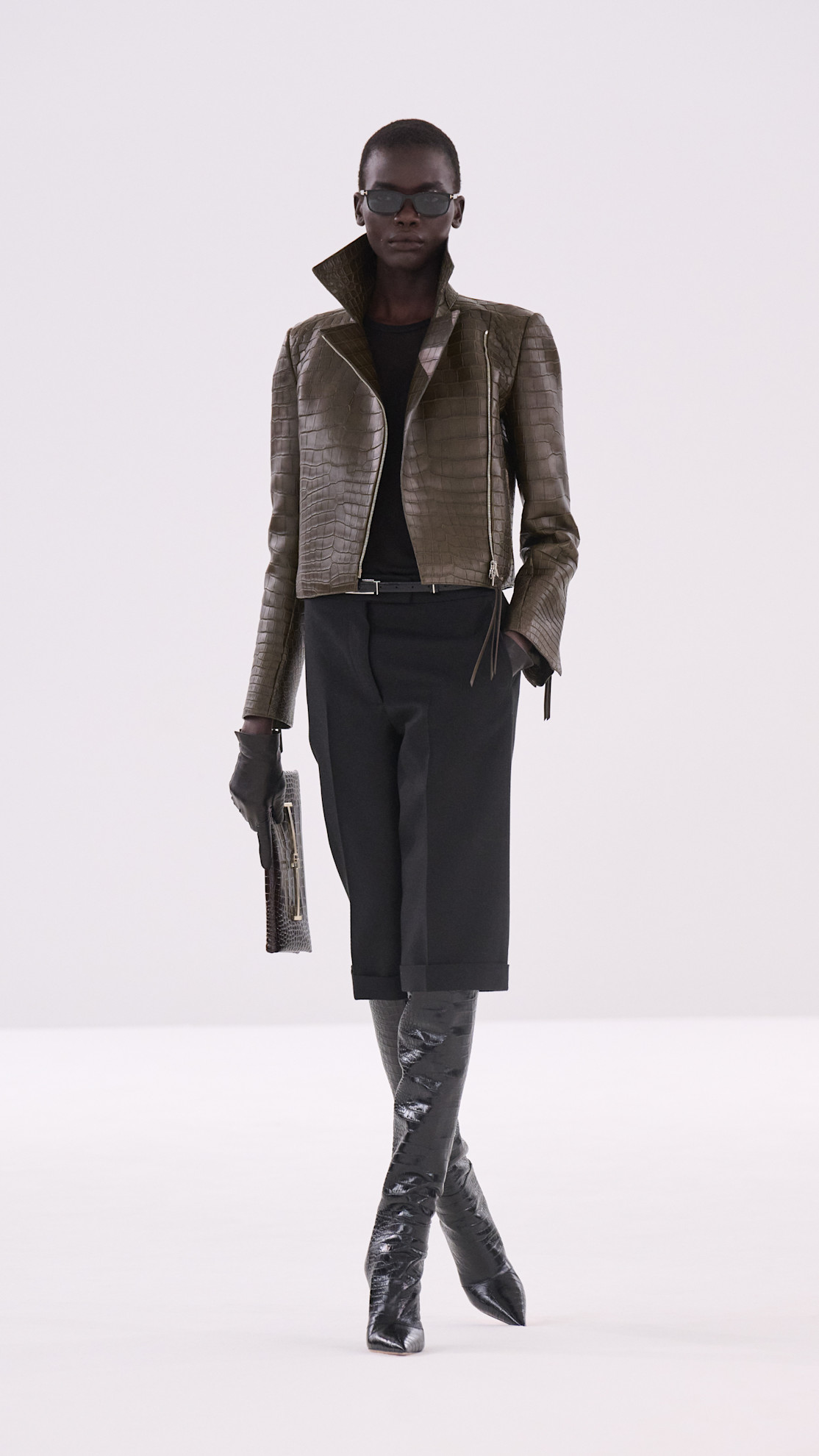 a Tom Ford model wearing a brown croc embossed cropped jacket, black culottes, and black boots