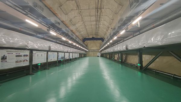 a smooth green floor reflects florescent lights shining above plastic-covered shelving, below a row of vents.