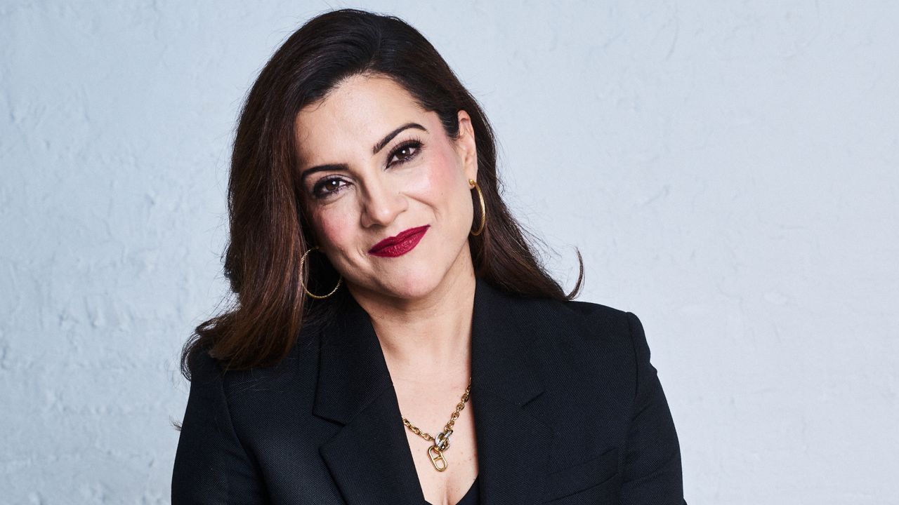 a headshot of girls who code founder reshma saujani as she smiles and wears a black blazer