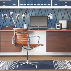 A home office with a built-desk and a brown leather ergonomic chair