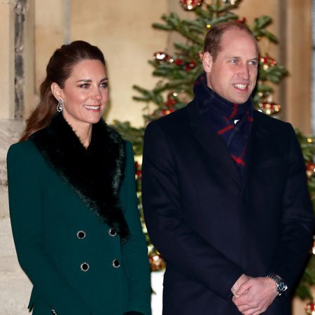 Kate Middleton wears a green winter coat with a large black fluffy collar and Prince William wears a large black overcoat and a tartan scarf