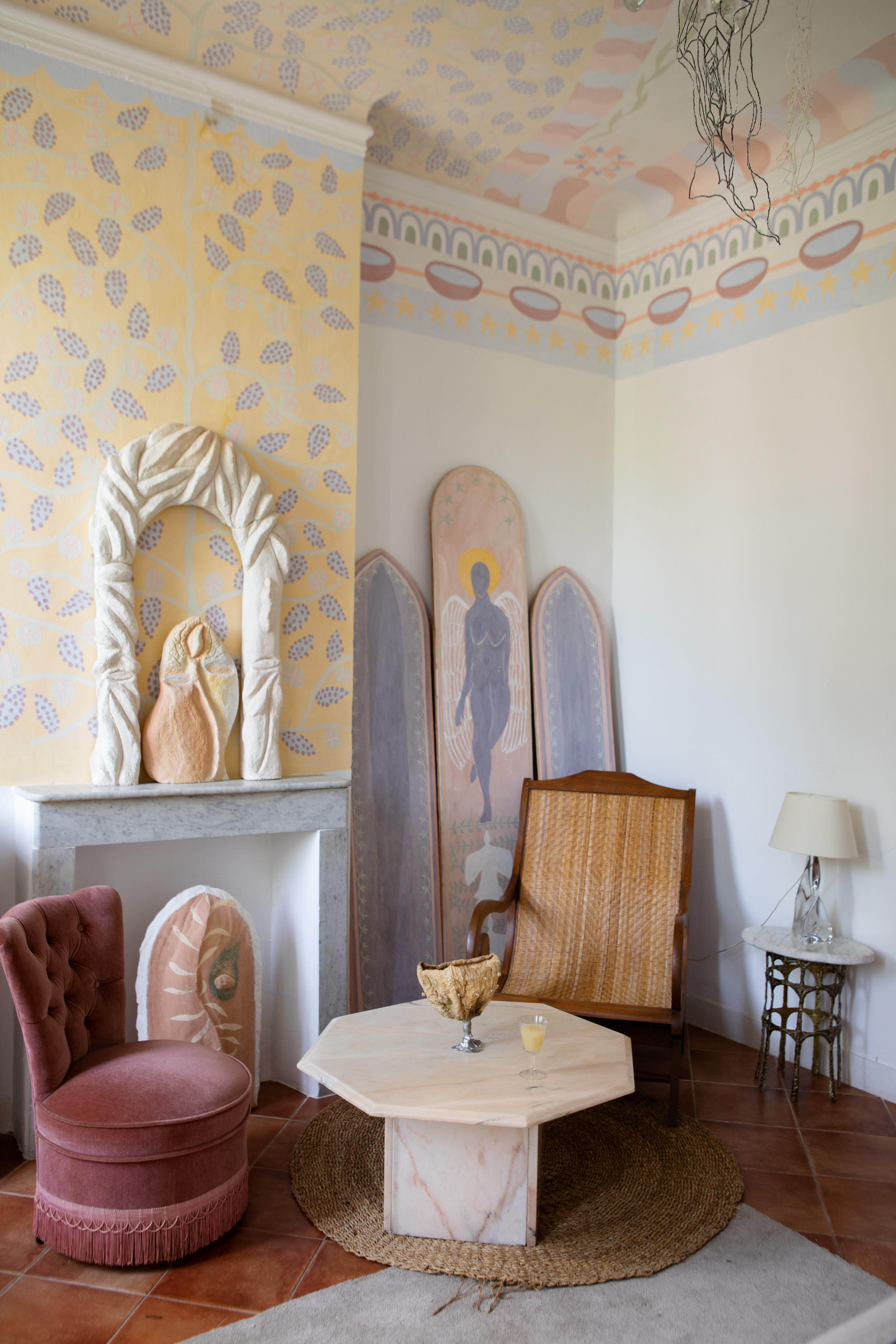 A beautifully renovated, palatial building with frescoed ceilings and walls houses an array of gothic-inspired furniture that simultaneously nod to contemporary and classical design, including tapestries, chandeliers, and velvety seats, and wooden decor.