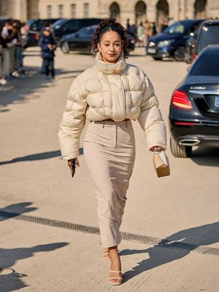 best down jackets, woman wearing creme cropped puffer coat with pencil skirt and sandals