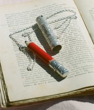 silver pencil holder on chain, resting on book