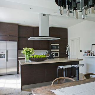 contemporary kitchen with dark wooden units and marble worktops