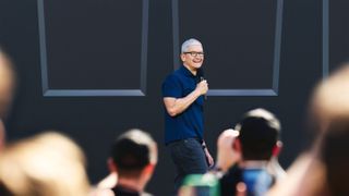 Tim Cook on stage holding a microphone at an Apple event