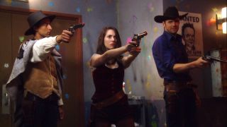 Danny Pudy, Alison Brie and Joel McHale dressed in Western costumes and holding paintball guns in Community