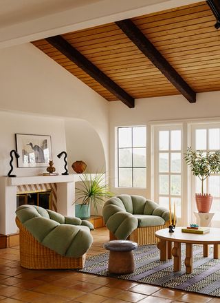 a living room with plump green chairs and a striped fireplace