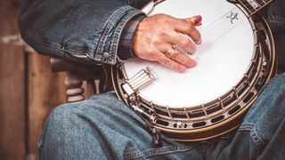 Close-up of man in denim playing the banjo