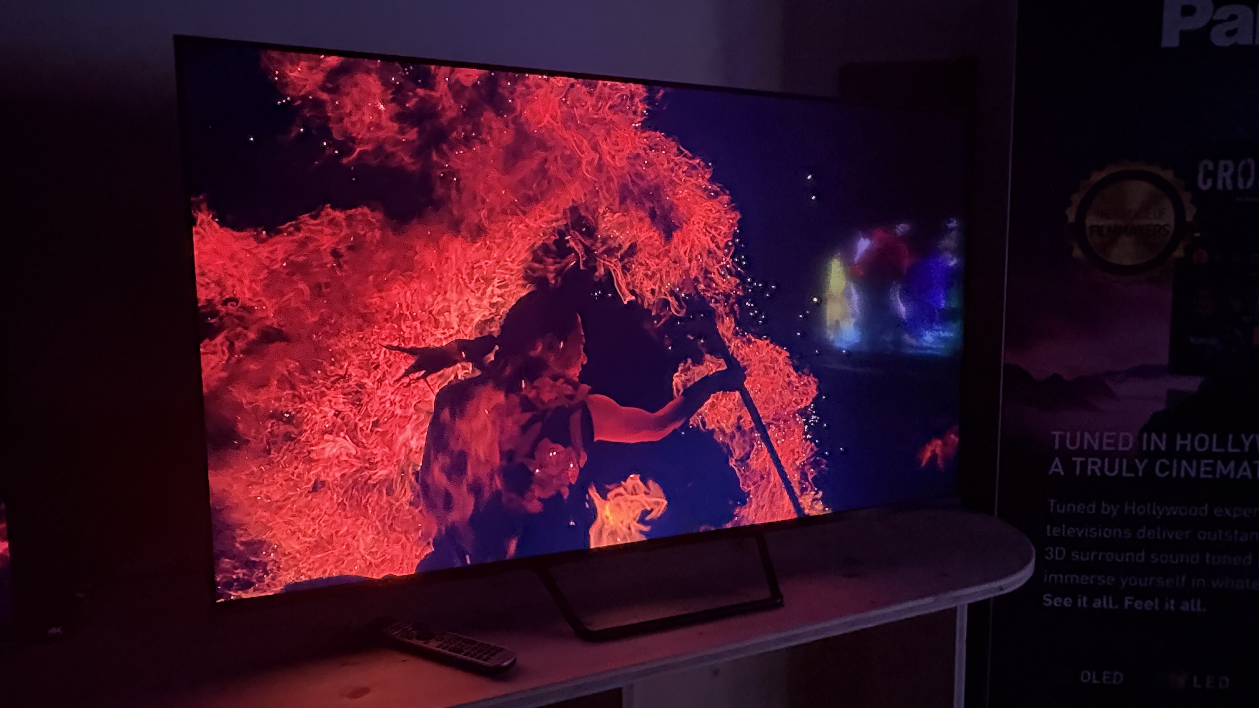 A Panasonic W95B TV in a dark room with a man wielding fire on screen