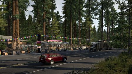 Cars pass in front of a roadside Bigfoot exhibit in American Truck Simulator