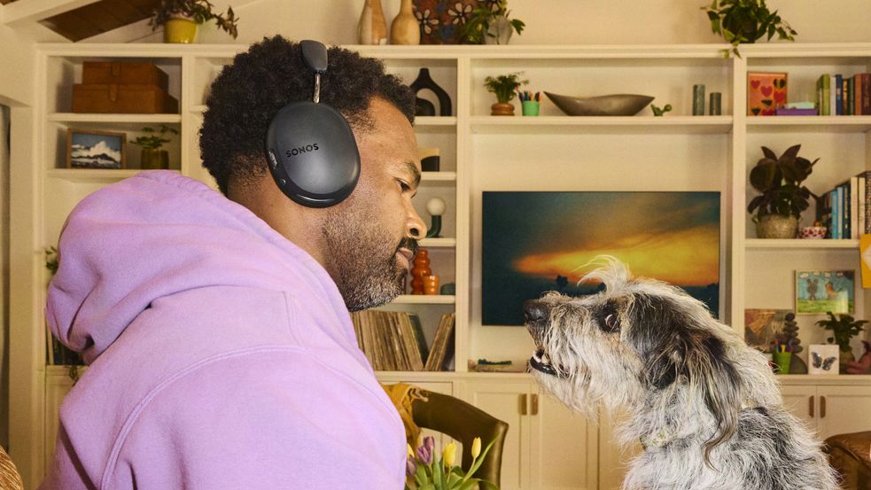 A man wearing Sonos Ace Ultra 2 headphones next to his dog