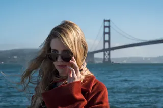 brit marling as prairie wearing a red coat and sunglasses by the golden gate bridge in the oa