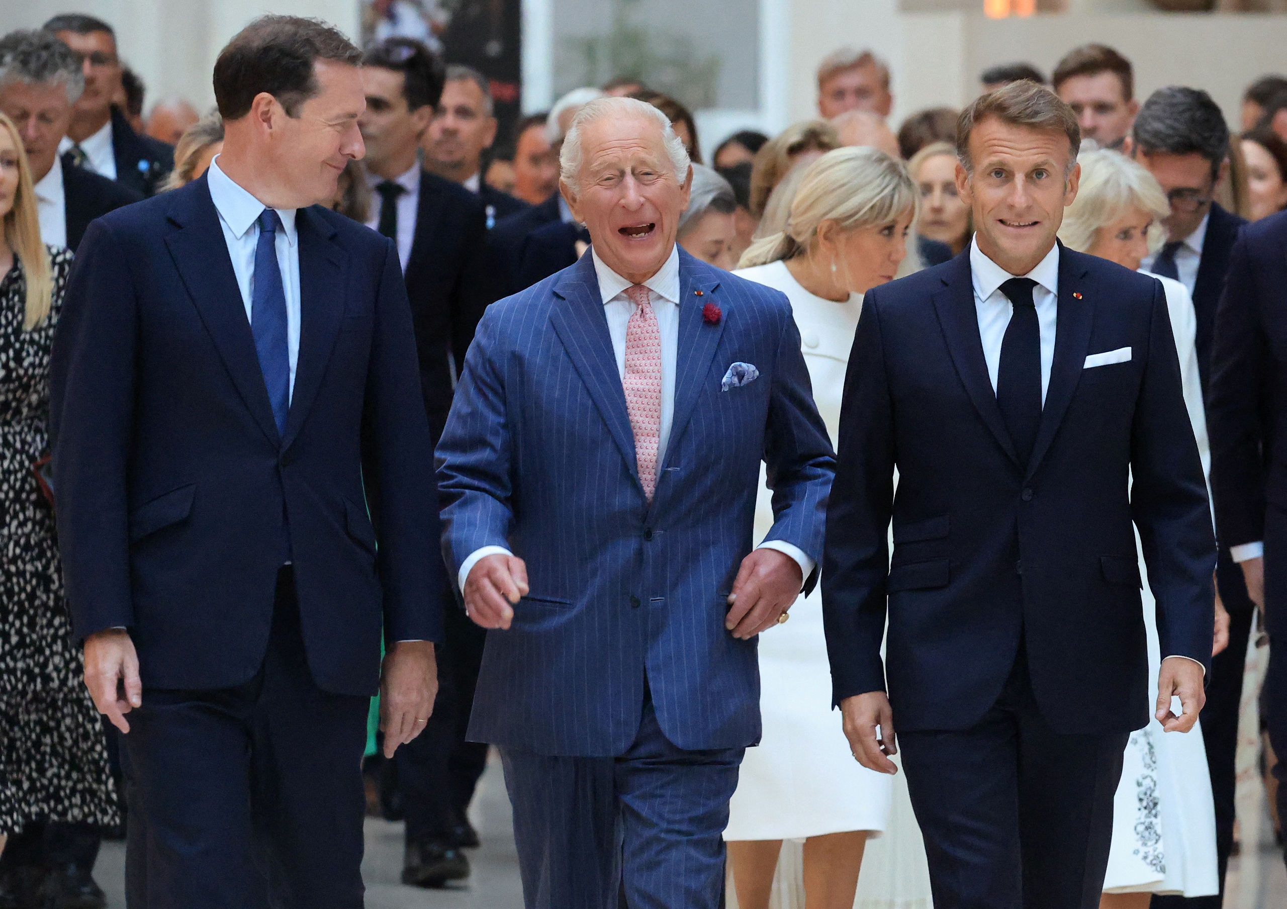 King Charles walking next to Emmanuel Macron and smiling