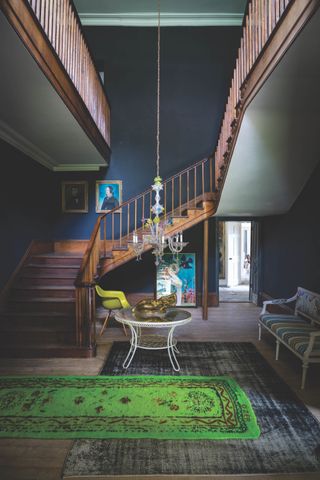 Μια σκούρα μπλε είσοδος με μεγάλη σκούρα ξύλινη σκάλα